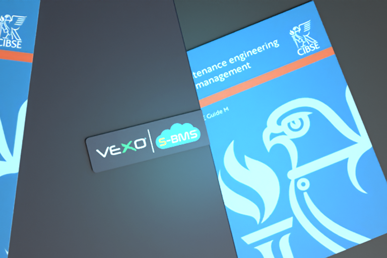Alt text: "A digital image featuring multiple copies of the CIBSE Guide M titled 'Maintenance Engineering and Management' with a blue cover displaying a stylized bird and torch emblem. The covers are dated 2023. To the right, there is a VEXO e-BMS device with a logo, indicating integration with building management systems.