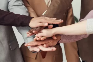 Diverse team of professionals standing in a circle with their hands stacked together, symbolizing unity and collaboration